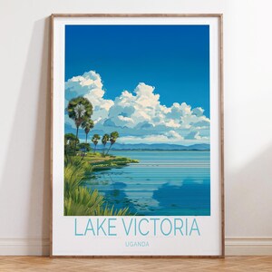 May include: A framed art print featuring a serene landscape of Lake Victoria in Uganda. The artwork showcases a vibrant blue sky with fluffy white clouds, palm trees, and the lake's calm waters. The text "LAKE VICTORIA UGANDA" is displayed at the bottom.