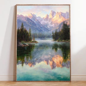 May include: A framed landscape painting depicts a mountain range reflected in a calm lake. The artwork features a color palette of blues, greens, and golden hues, with evergreen trees lining the water's edge. The painting is encased in a wooden frame.