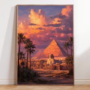 May include: Framed art print of an Egyptian sunset scene. The image shows the pyramids, Sphinx, and palm trees under a sky of orange and purple clouds. The artwork is presented in a wooden frame.