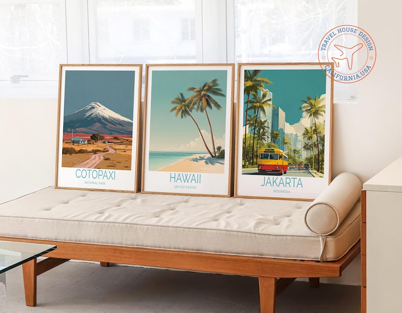 May include: Three framed travel art prints featuring scenic destinations: Cotopaxi National Park, Hawaii, and Jakarta, Indonesia. Each print has a wooden frame and showcases vibrant illustrations of landscapes and landmarks. The prints are displayed on a wooden bench.