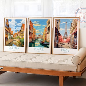 Puede incluir: Tres p&oacute;sters de viaje enmarcados con ilustraciones de estilo vintage de Colmar, Francia; Venecia, Italia; y Par&iacute;s, Francia. Cada p&oacute;ster presenta el nombre de la ciudad y el pa&iacute;s en una fuente azul.