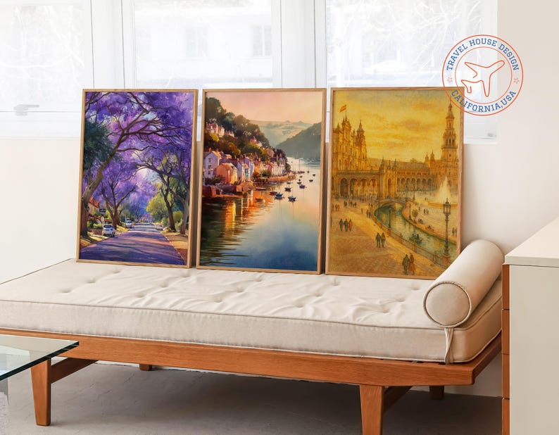 May include: Three framed watercolor prints. The left print depicts a street lined with purple flowering trees. The middle print shows a coastal town. The right print features a European building with a fountain.