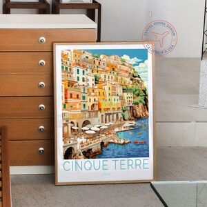 May include: A vintage travel poster featuring a colourful illustration of the Cinque Terre region in Italy. The poster has a blue sky, a turquoise sea, and a hillside town with colourful buildings. The text on the poster reads "Cinque Terre, Italy".