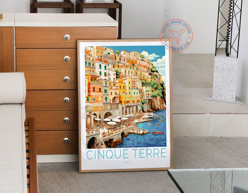 May include: A vintage travel poster featuring a colourful illustration of the Cinque Terre region in Italy. The poster has a blue sky, a turquoise sea, and a hillside town with colourful buildings. The text on the poster reads "Cinque Terre, Italy".