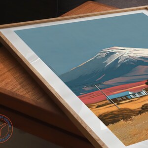 May include: Framed art print featuring a mountain landscape with a snow-capped peak, a blue sky, and a house. The artwork has a white border and a natural wood frame. The print has a Travel House Design California USA logo.