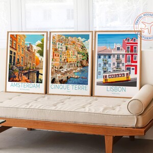 May include: Three framed travel posters with colourful illustrations of Amsterdam, Cinque Terre, and Lisbon. Each poster features the city name, country, and a small aeroplane icon.