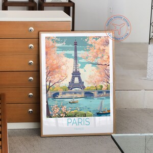 May include: A vintage travel poster featuring a colorful illustration of the Eiffel Tower in Paris, France. The poster has a blue sky with pink cherry blossoms and a river with boats. The text "PARIS FRANCE" is at the bottom of the poster.