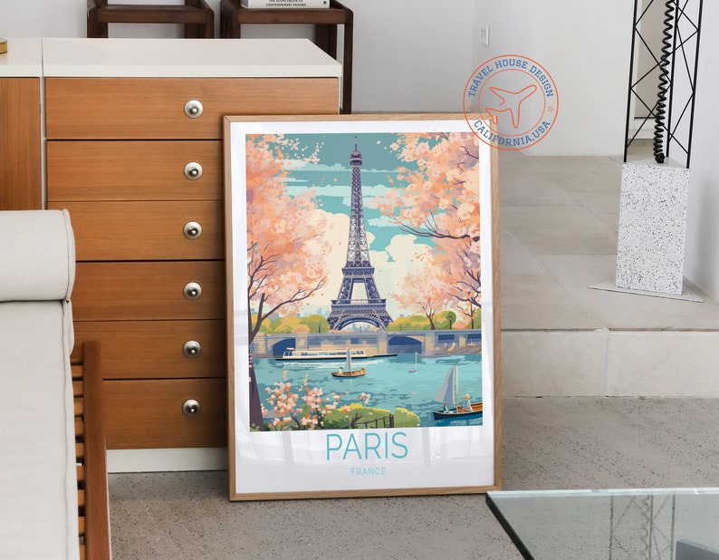 May include: A vintage travel poster featuring a colorful illustration of the Eiffel Tower in Paris, France. The poster has a blue sky with pink cherry blossoms and a river with boats. The text "PARIS FRANCE" is at the bottom of the poster.