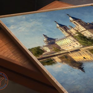 May include: A framed print of a European palace reflected in water. The artwork features a light wooden frame and a detailed depiction of the building's architecture, with a blue sky and water. The Travel House Design logo is visible in the lower left corner.
