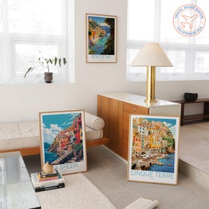 May include: Three framed travel posters featuring Italian coastal scenes. One poster displays "Portofino", another "La Spezia", and the third "Cinque Terre". The posters have a vintage travel aesthetic with vibrant colors and detailed illustrations.