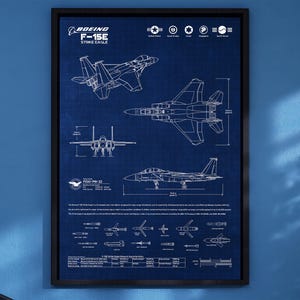Puede incluir: Póster enmarcado estilo plano de la Boeing F-15E Strike Eagle. El póster presenta dibujos técnicos detallados de la aeronave en varias vistas, con el logotipo de Boeing y texto en la parte superior. El fondo es de color azul oscuro.