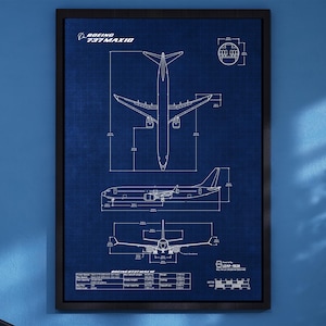 May include: Framed blueprint of a Boeing 737 MAX 10 aircraft, set against a blue backdrop. The blueprint shows top, side, and front views, with dimensions and specifications. The frame is black.