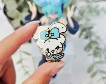 Puede incluir: Un pin de esmalte blanco con un conejito de dibujos animados que lleva un lazo azul. El conejito tiene mejillas rosadas y sonríe. El pin es de color dorado.
