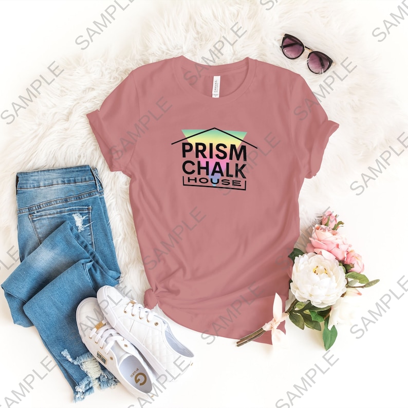 May include: A pink t-shirt with a graphic of a house with a rainbow prism design and the text "PRISM CHALK HOUSE" in black.