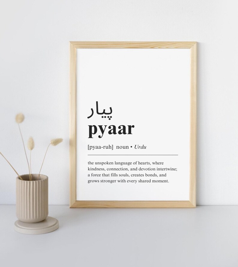 May include: A framed print with a black and white definition of the Urdu word "pyaar" which means love. The definition reads: "the unspoken language of hearts, where kindness, connection, and devotion intertwine; a force that fills souls, creates bonds, and grows stronger with every shared moment."