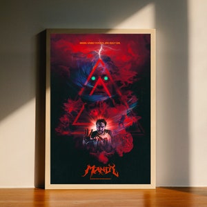 May include: A movie poster with a red and black colour scheme. The poster features a man with a shocked expression, standing in front of a red triangle with a glowing green eye. The text on the poster reads "Bikers, crazy psychos, and crazy evil. MANDY".