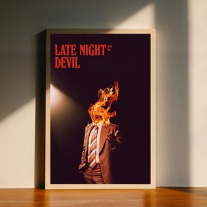 May include: A poster with the text "LATE NIGHT with the DEVIL" in red letters. The poster features a man in a brown suit with flames coming out of his head.