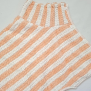 May include: A peach and white striped towel with a high neck and snap closures.