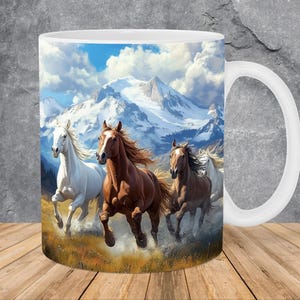 Puede incluir: Una taza de cerámica blanca con una imagen colorida de cuatro caballos corriendo a través de un paisaje montañoso. Los caballos son marrones, blancos y negros, y las montañas están cubiertas de nieve. El cielo es azul con nubes blancas.