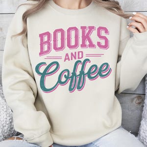 Pu&ograve; includere: Felpa beige con la scritta "BOOKS AND Coffee" in rosa e verde acqua. Il testo &egrave; centrato sul davanti. La felpa ha maniche lunghe e girocollo.