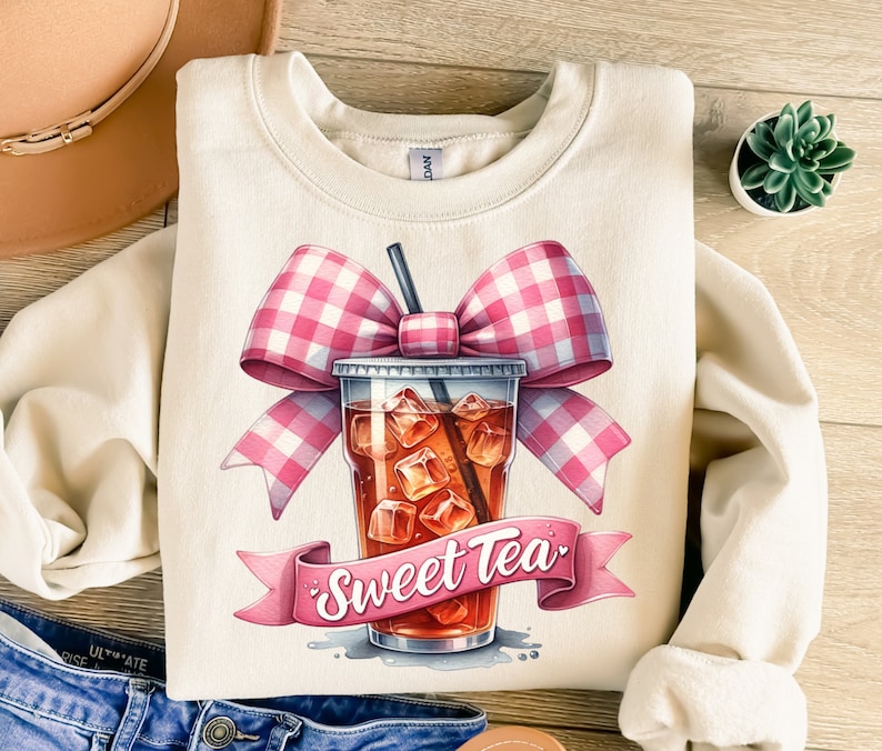 May include: A beige sweatshirt with a graphic of a pink and white gingham bow on top of a glass of iced tea with the text "Sweet Tea".