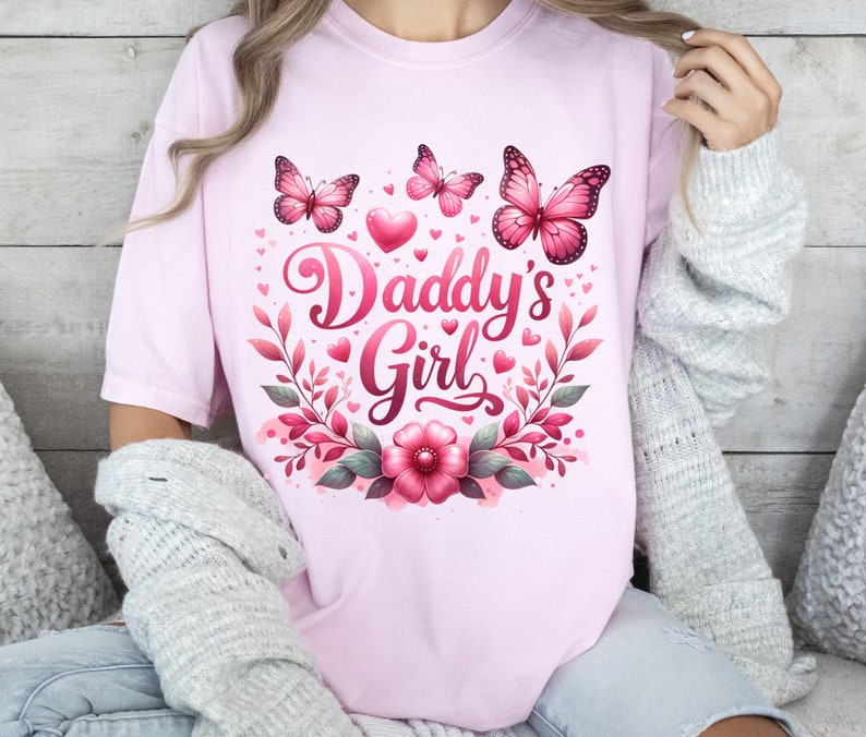 May include: Pink t-shirt with a floral design and butterflies. The text "Daddy's Girl" is written in a decorative font.