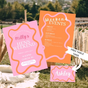 May include: Pink and orange event signage with the text "Milly's Hens Weekend" and "Weekend Events." Includes a table tag with the name "Ashley." The design features a wavy border and is set against a natural outdoor backdrop.