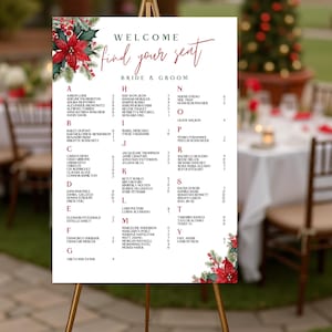 May include: A welcome sign for a wedding, featuring the text "Welcome, find your seat" in elegant script. The sign lists guest names alphabetically, with floral accents of red poinsettias and greenery.