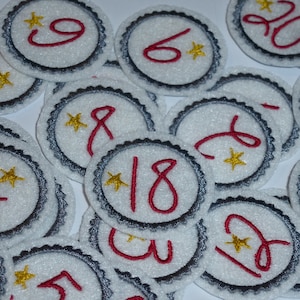 May include: White felt circles with black trim and red numbers from 1 to 20. Each circle has a gold star.