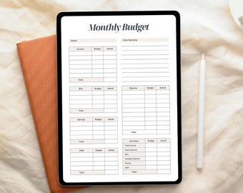 May include: A digital tablet showing a "Monthly Budget" template, with sections for income, bills, savings, and debt. A white stylus and an orange notebook are next to the tablet. The template is designed for financial planning.