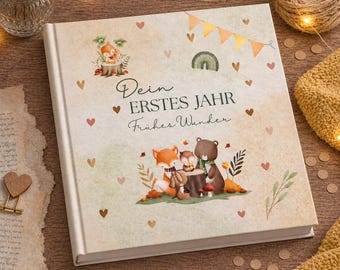 May include: A hardcover baby memory book with the German text "Dein Erstes Jahr Frühes Wunder" (Your First Year Early Wonder). The cover features illustrations of woodland animals, hearts, and a rainbow in a soft, neutral color palette.