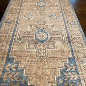 Könnte beinhalten: Ein Vintage-Läufer mit einem geometrischen Muster in Braun-, Blau- und Beigetönen. Der Teppich hat einen verblassten, abgenutzten Look und ist perfekt, um jedem Raum einen Hauch von rustikalem Charme zu verleihen.