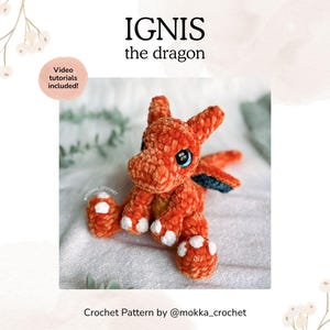 May include: An orange crochet dragon named Ignis with white accents on its feet and a blue wing. The image includes the text "IGNIS the dragon" and "Video tutorials included!" The crochet pattern is by @mokka_crochet.