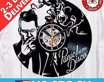Könnte beinhalten: Schwarze Schallplattenuhr mit einer Silhouette einer Person, die raucht, mit dem Text "Panic! at the Disco" in weißen Buchstaben.