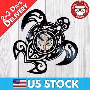 May include: Black vinyl record clock shaped like a turtle with intricate details. The clock face has a silver background with black numbers and hands. The clock is mounted on a wooden surface.