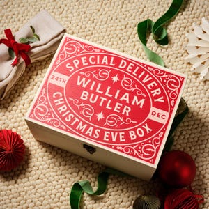 May include: A white wooden box with a red and white design. The box has the text "Special Delivery" and "Christmas Eve Box" on it. The box also has the name "William Butler" on it.