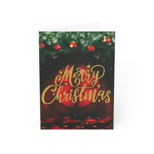 May include: A Christmas card with a festive design. The front displays the words "Merry Christmas" in gold script over a red background. The top has green pine branches and red baubles.