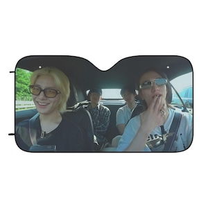 May include: A car sunshade featuring a photo of four people in a car. The people are wearing sunglasses and casual clothing. The sunshade is black and has a rectangular shape.