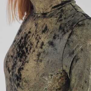 May include: A gold and black long-sleeved shirt with a high neck and a textured, sparkly fabric.