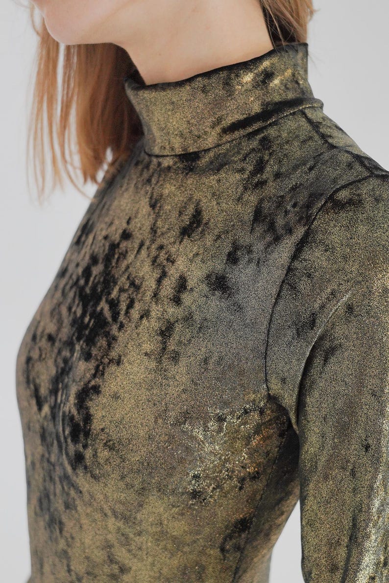 May include: A gold and black long-sleeved shirt with a high neck and a textured, sparkly fabric.