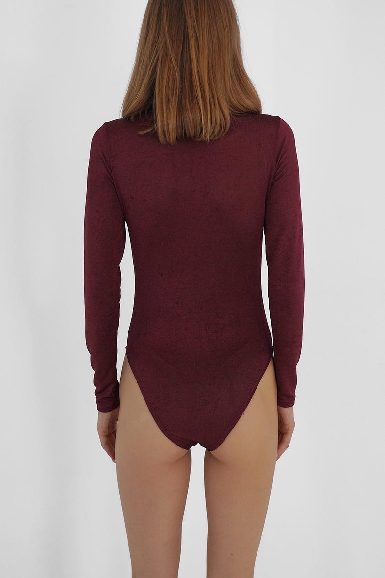 Puede incluir: Un body de manga larga color burdeos con cuello alto.