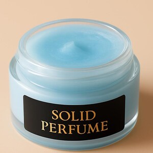 May include: A small, clear glass jar filled with light blue solid perfume. The jar has a black label with the words "SOLID PERFUME" in gold lettering. The perfume has a smooth, slightly domed surface.