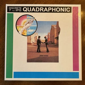 May include: A vintage album cover with the text "DISCRETE QUADRAPHONIC" at the top. The cover features a circular graphic with a handshake and a sunset, and two men shaking hands in front of a building. The album is a 7 1/2 IPS.