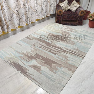 May include: A light blue, brown, and white abstract patterned rug with the text "FLOORING ART" in the center.