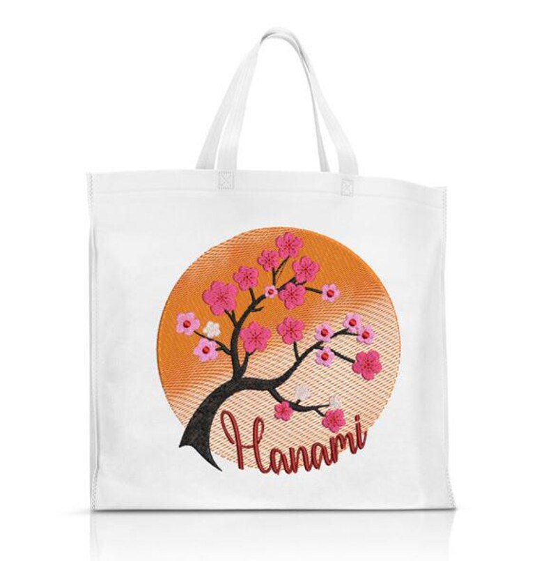 May include: White tote bag with an embroidered design of a pink cherry blossom tree in front of an orange sun. The text "Hanami" is embroidered below the tree.