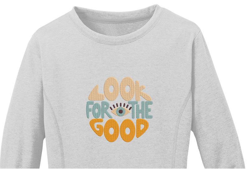 Pu&ograve; includere: Una felpa grigia chiaro a maniche lunghe con il testo "Look for the good" in un cerchio con un occhio stilizzato al centro. Il testo &egrave; in un font retr&ograve; con colori arancio, giallo e blu.