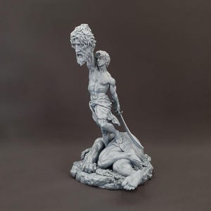 May include: A gray resin sculpture depicting a figure standing over a fallen body, holding a severed bearded head aloft in one hand and a curved sword in the other. The figure wears a draped cloth around the waist, with detailed musculature.