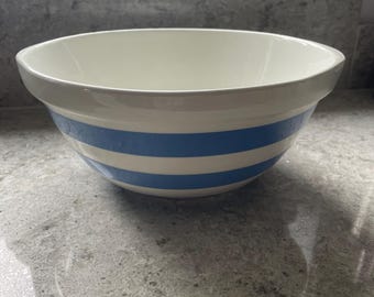 Może przedstawiać: Biała ceramiczna miska do mieszania z dwoma poziomymi niebieskimi paskami. Miska ma szeroki brzeg i gładkie wnętrze. Miska stoi na szarym blacie.