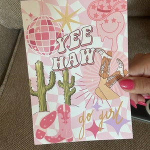 Può includere: Stampa rosa e oro con il testo "Yee Haw" e "go girl" con una palla da discoteca, un cactus, un cappello da cowboy e stivali.