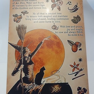 May include: A vintage-style metal sign with a witch holding a broom and a cauldron. The sign has a yellow background with a large orange moon and a black cat. The text on the sign reads "A Witch's Kitchen Blessing" and includes a blessing for the kitchen.